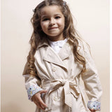 Gabardina de niña beige con cinturón y puños de flores.