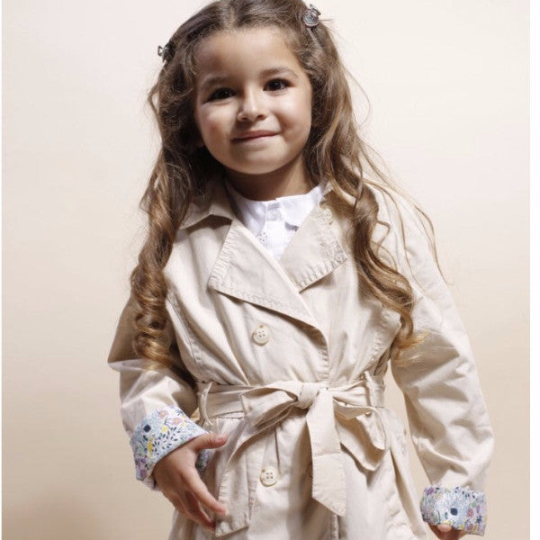 Gabardina de niña beige con cinturón y puños de flores.